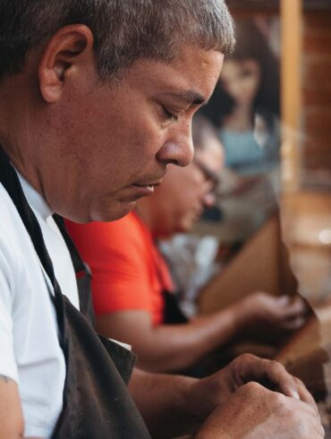 a person in an apron looking at a piece of paper - making a cigar