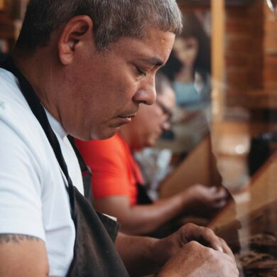 a person in an apron looking at a piece of paper - making a cigar
