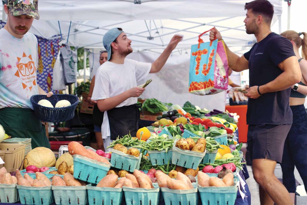 a person handing a bag to another person at a farmers market